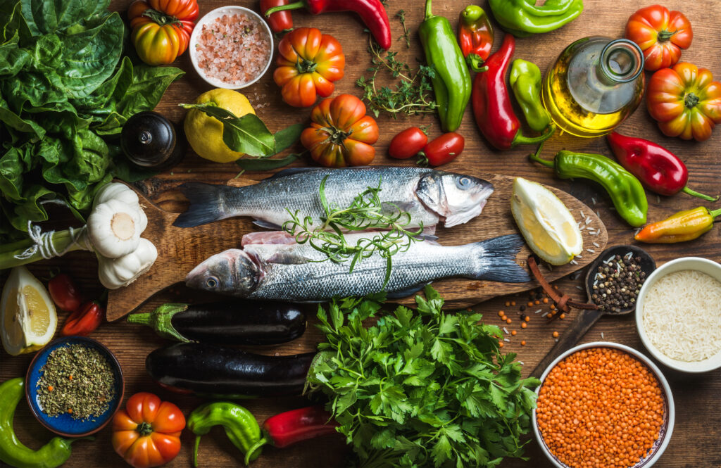 Raw uncooked seabass fish with vegetables, grains, herbs and spices on chopping board over rustic wooden background, top view. mediterranean diet
By sonyakamoz