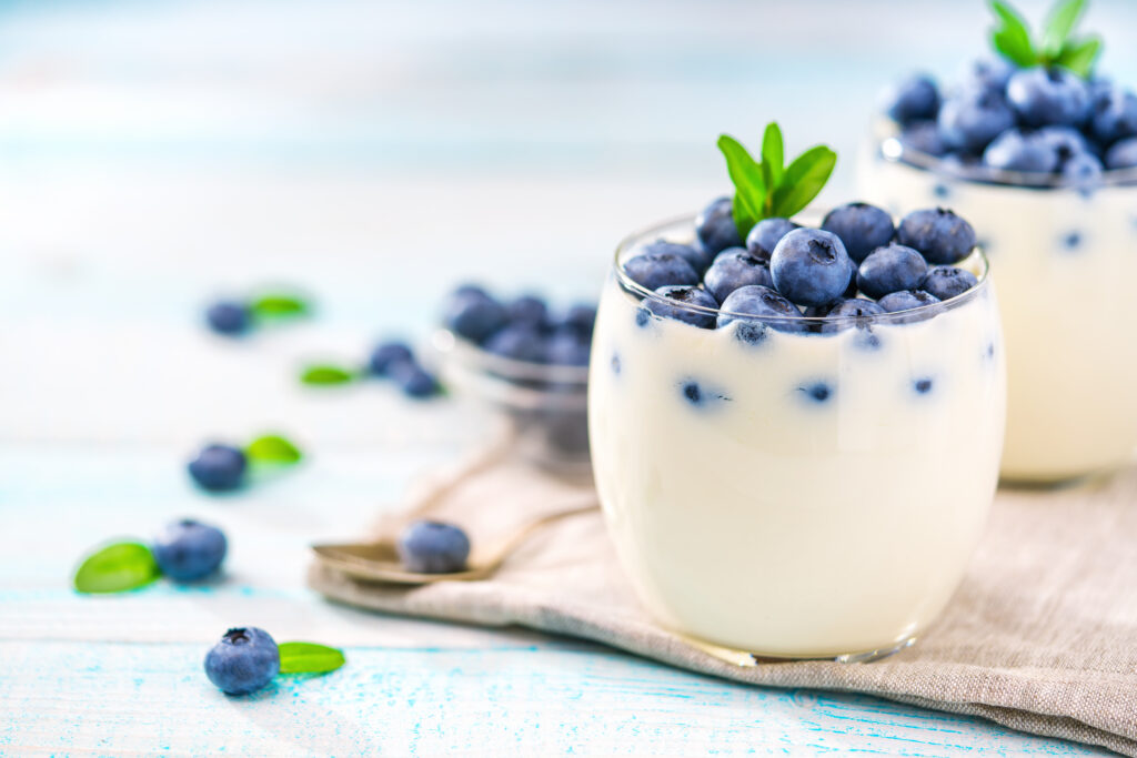 Homemade  greek yogurt, and fresh berries blueberries in a  jar with a spoon over rustic wooden background By Igor Dudchak