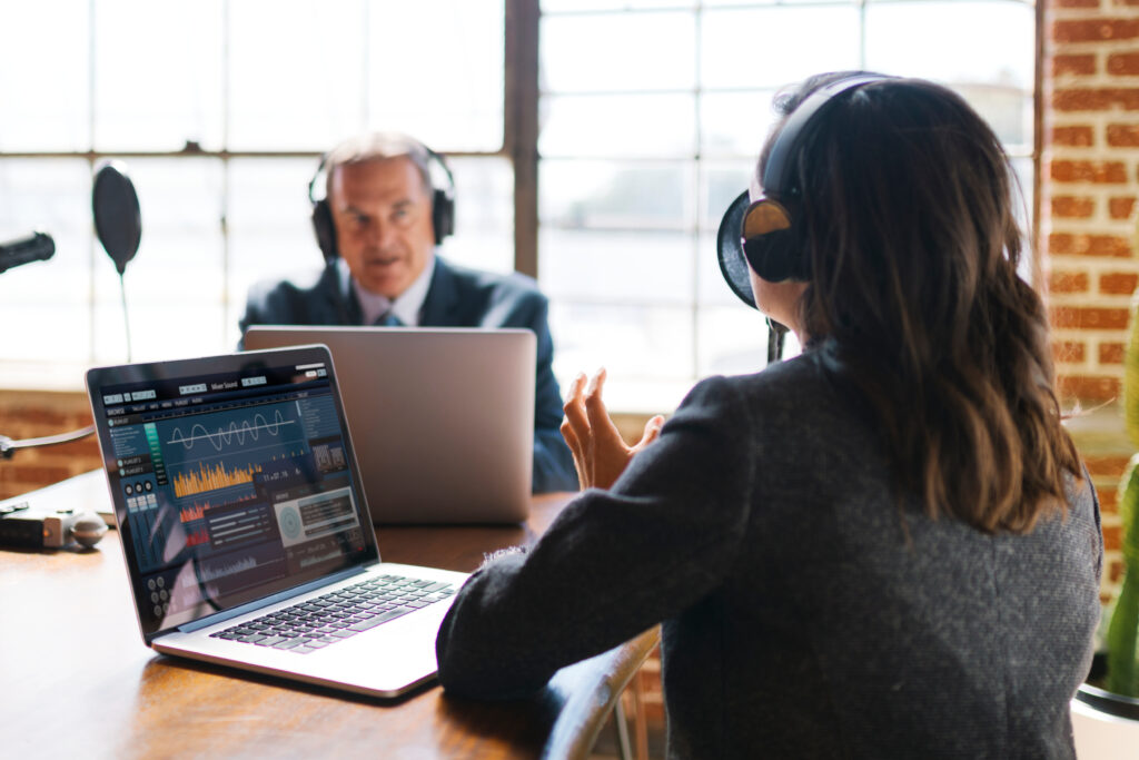 photo of podcast host interviewing guest with laptops and headset speaking into microphone By rawpixel.com