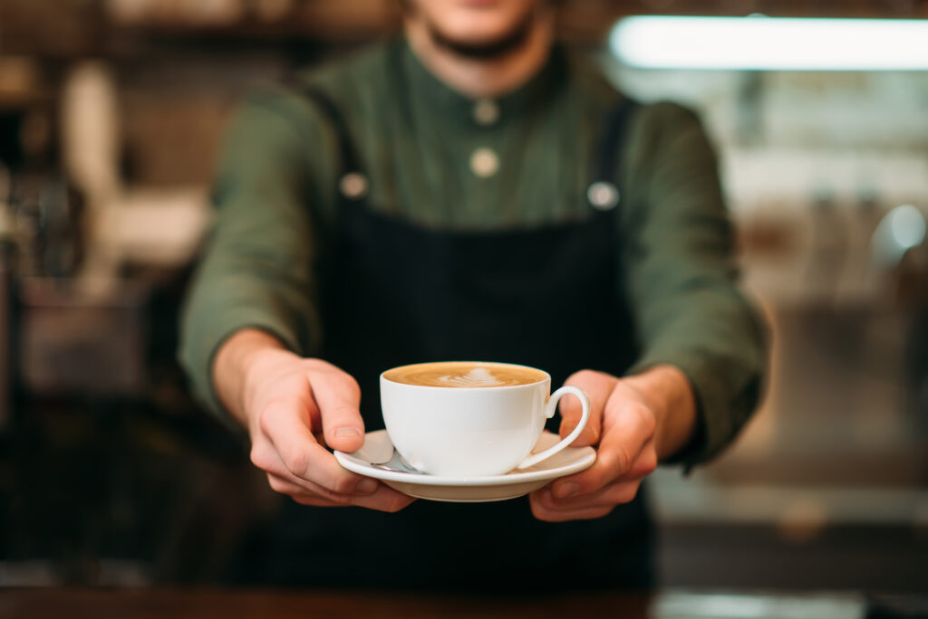 Waiter in black apron stretches a cup of coffee By Nomad_Soul