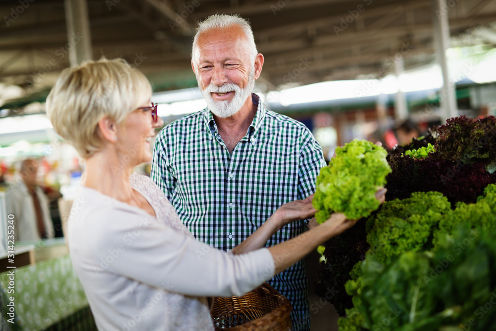 Mature couple shopping vegetables and fruits on the market. Healthy diet. photo by NDABCREATIVITY adobe stock
